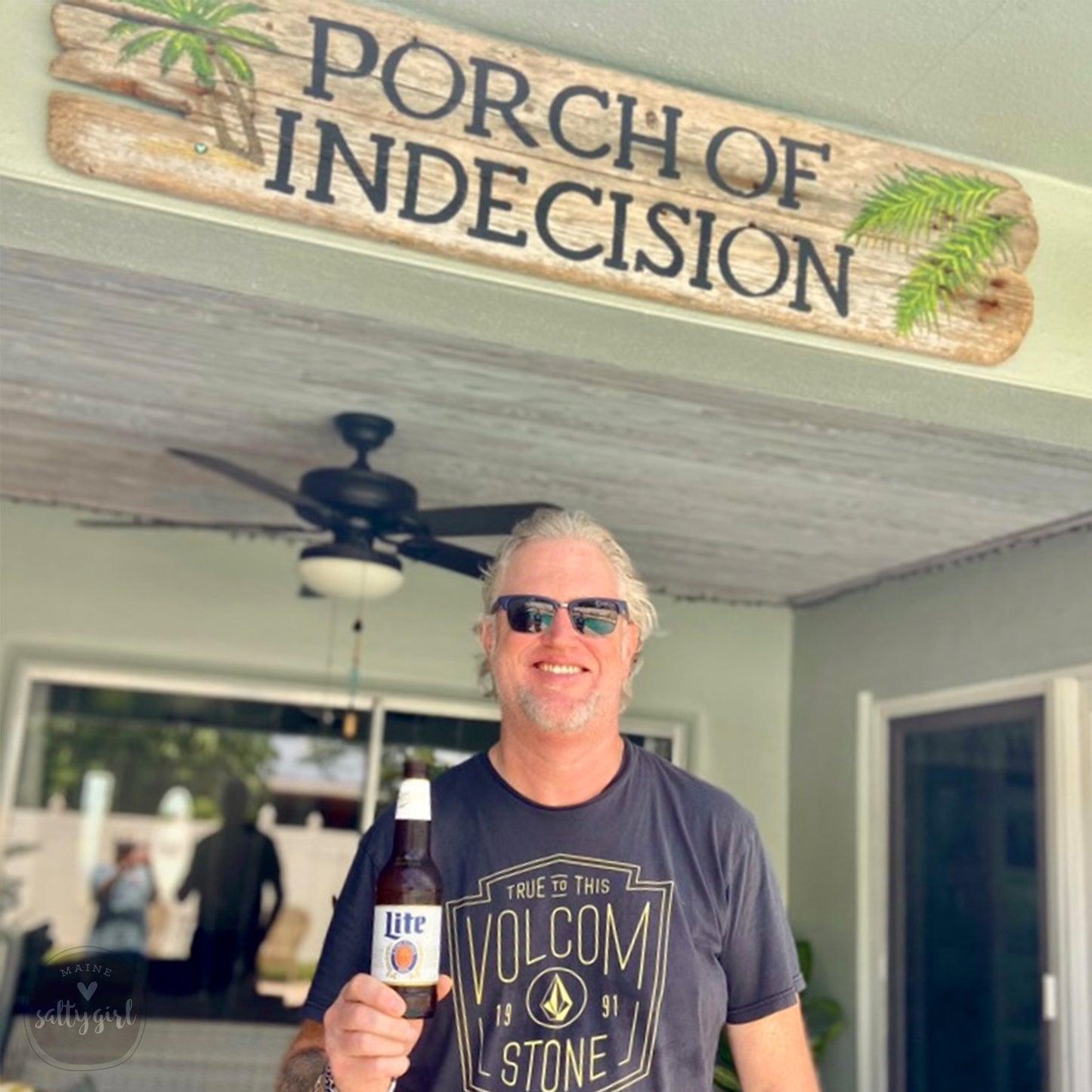a man holding a bottle of beer in front of a sign