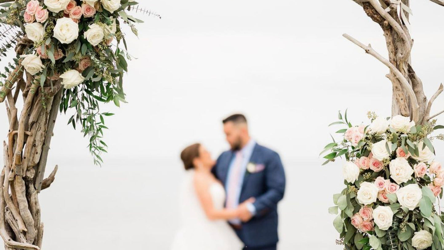 a bride and groom standing under a wooden arch