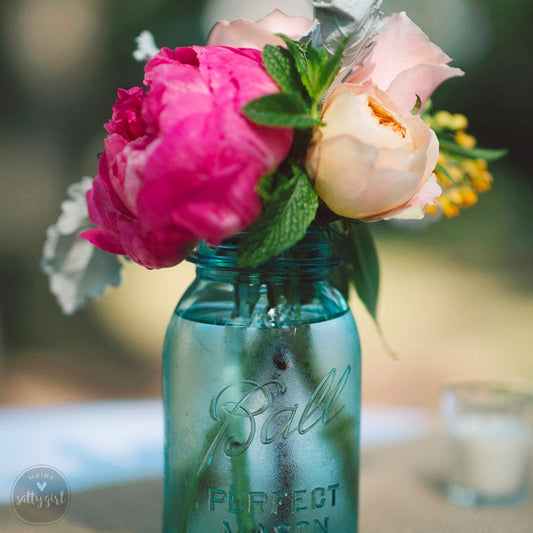a blue mason jar with pink and white flowers in it