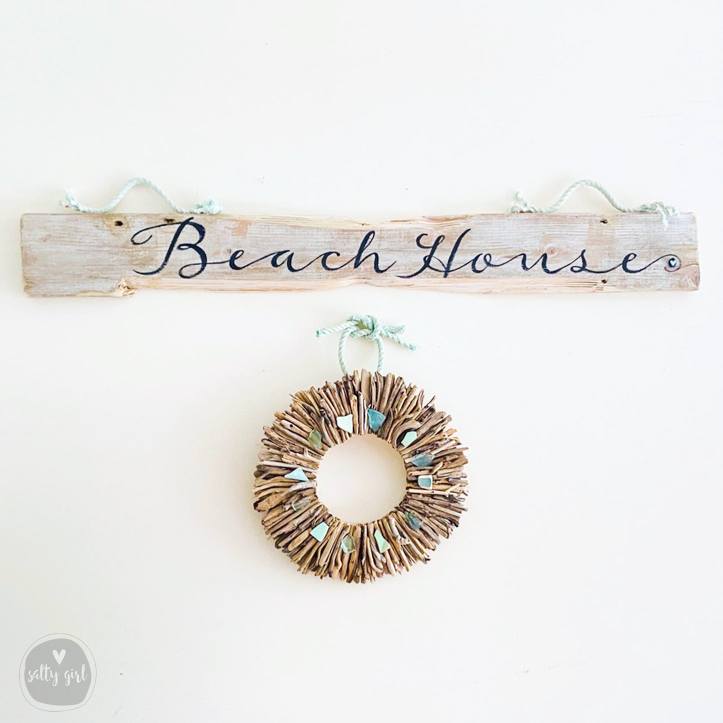a wooden sign that says beach house with a wreath hanging from it