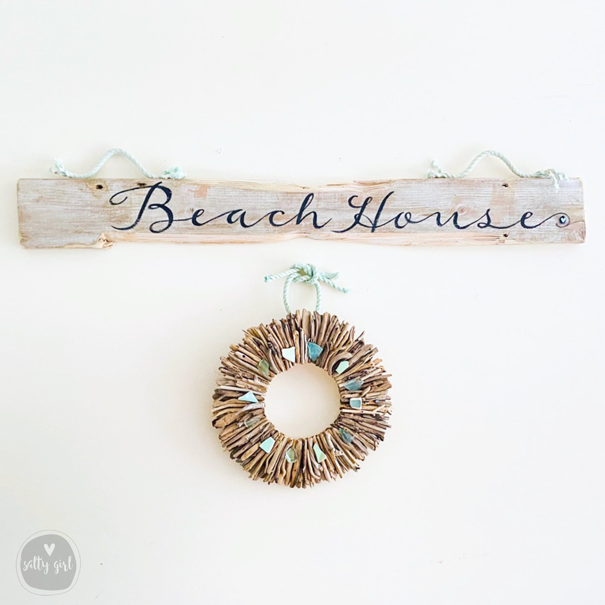 a wooden sign that says beach house with a wreath hanging from it