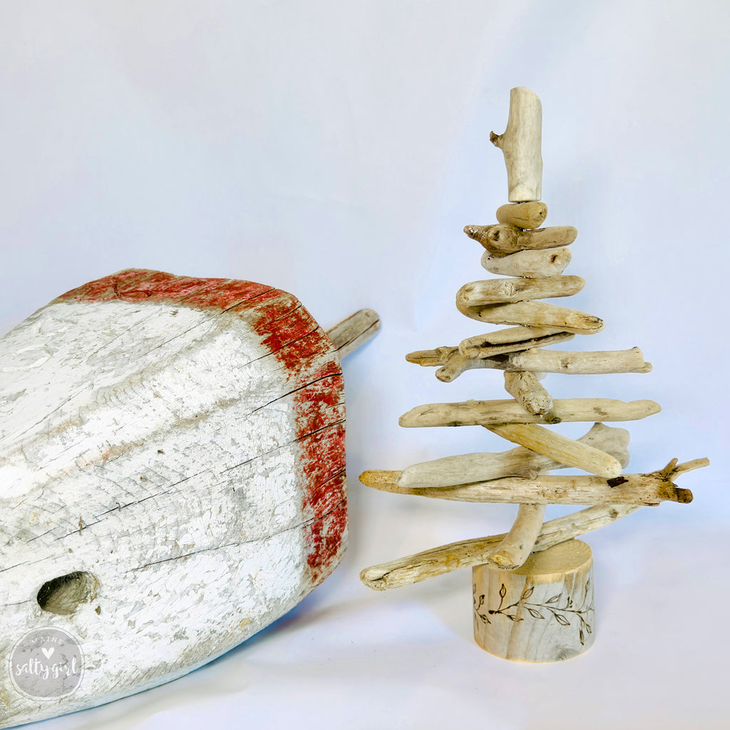 a rustic driftwood Christmas tree made from various driftwood pieces, including a large driftwood log with a red stripe on it, and a smaller driftwood tree made from smaller branches.