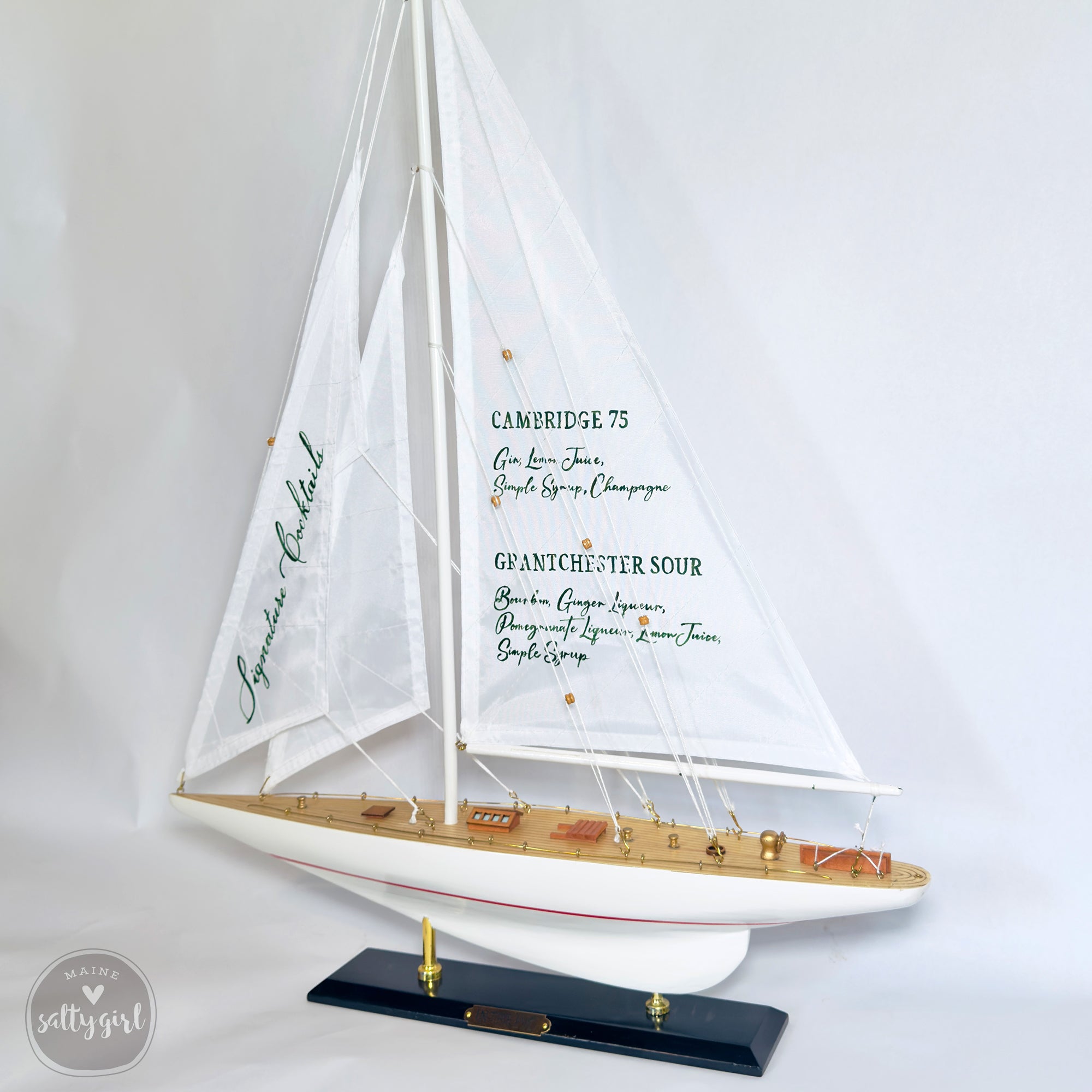 A model of a sailboat with a white hull and green sails, displaying the names of the wines it is sailing.