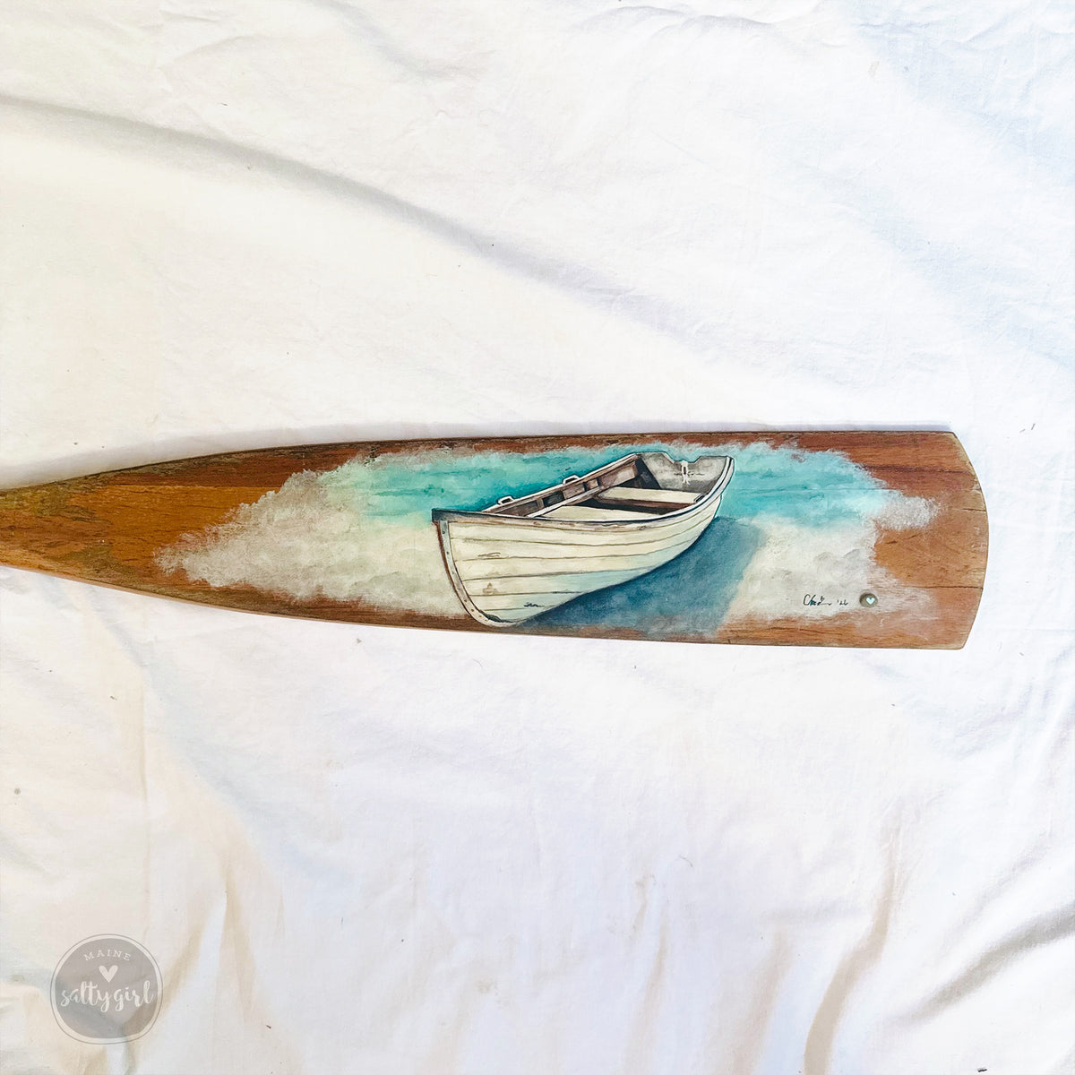 a wooden paddle with a painted image of a boat on it.