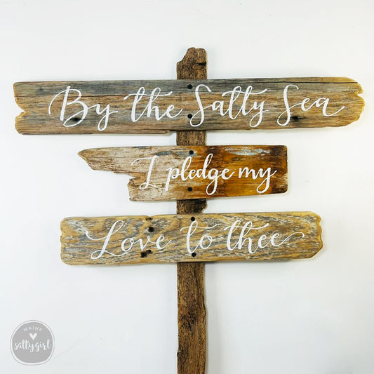 a wooden sign with a message about the sea, including the words "By the Salty Sea" and "Ipledge my Love to thee".