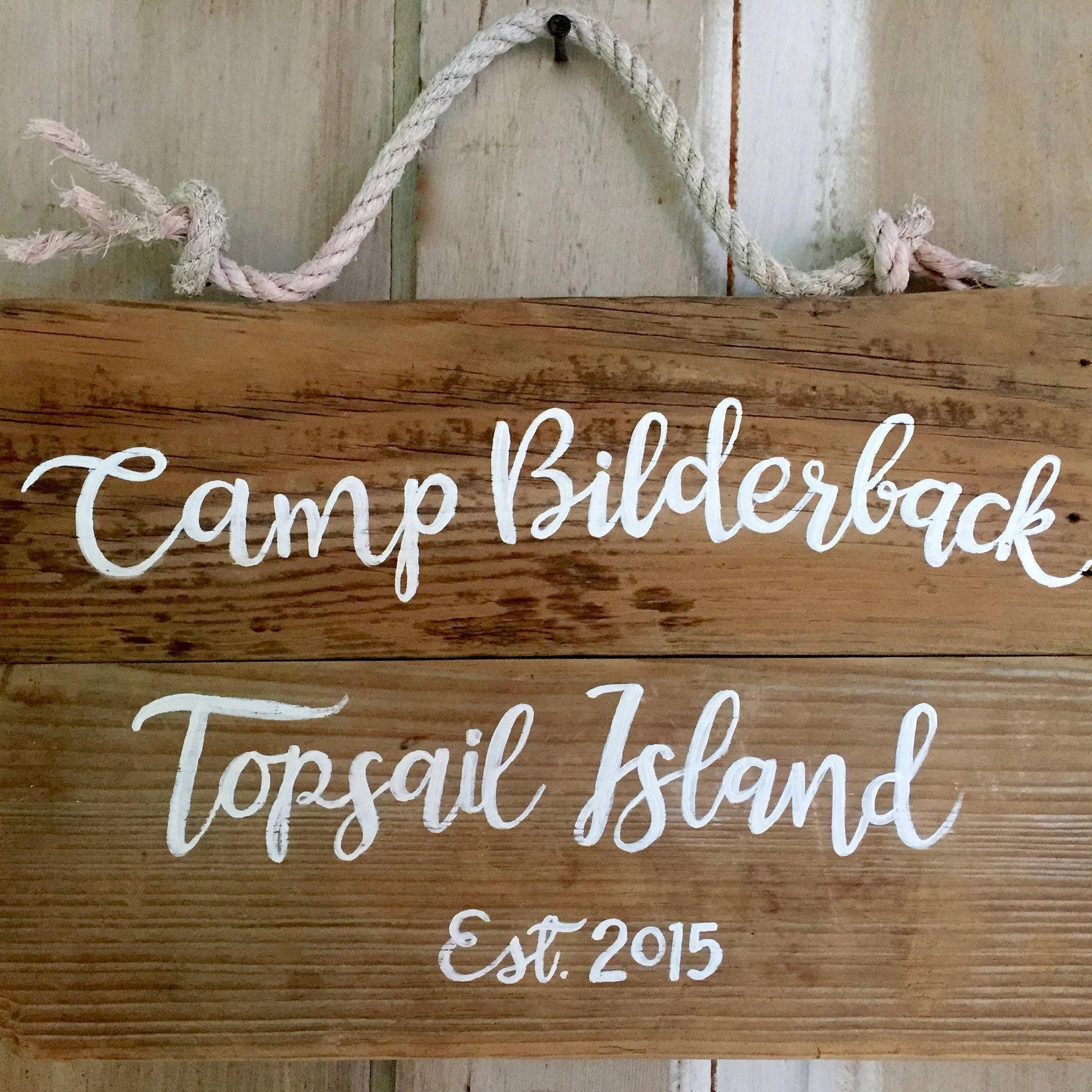 A wooden sign with the name "Camp Bilderback" and " topsail island" written on it, along with the year "Est. 2015".