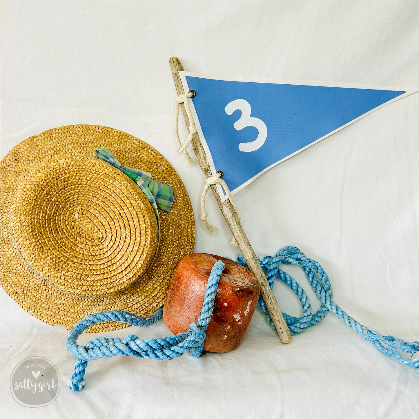 a straw hat and a blue and white flag on a white sheet