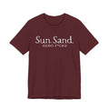 A burgundy-colored t-shirt with the text "Sun. Sand. Zero F*cks" printed on it.
