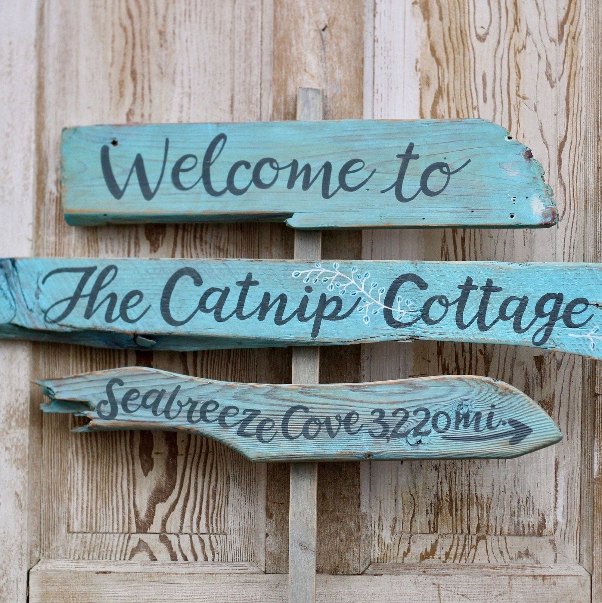 a wooden sign with the text "Welcome to The Catnip Cottage" and "Seabreeze Cove 322m" written on it.
