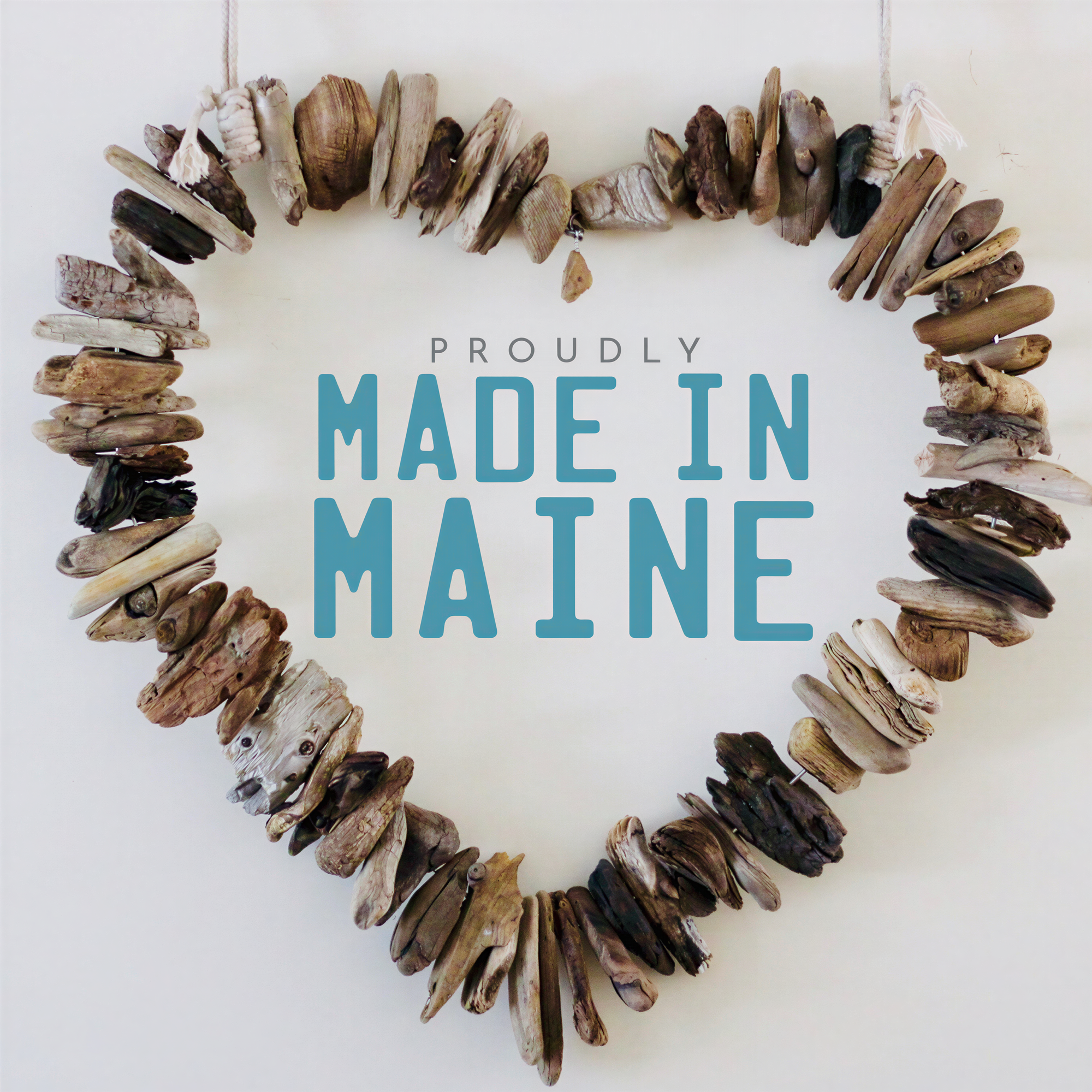 A heart-shaped arrangement of various natural materials, including sticks, stones, and leaves, with the text "PROUDLY MADE IN MAINE" displayed prominently in the center.