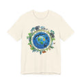 A white Maine Salty Girl t-shirt with a graphic design depicting a colorful illustration of the Earth surrounded by various animals and plants, along with the text "FEEL THE BODY OF THE EARTH DANCE THE SONG OF LIFE".