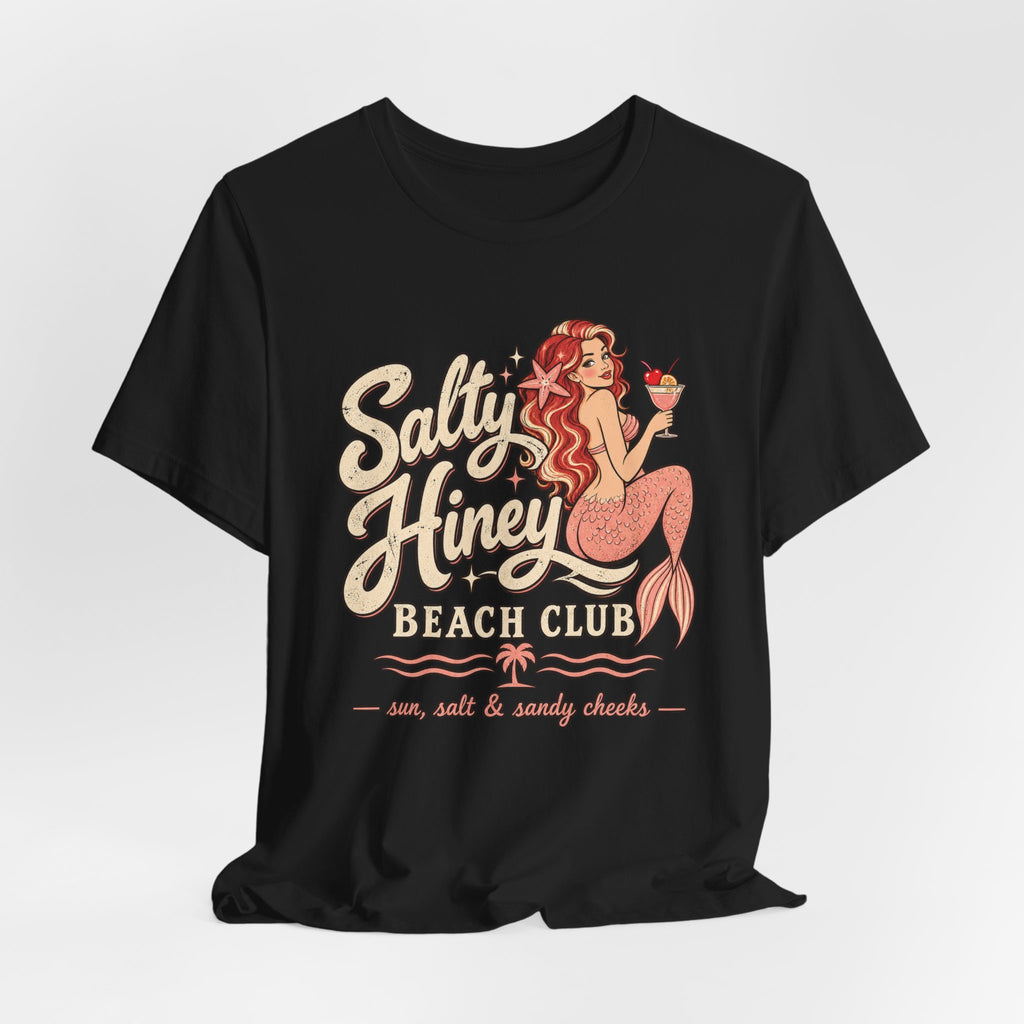 A black t-shirt with a graphic design featuring a mermaid character and text that says "Salt Honey Beach Club sun, salt & sandy cheeks".