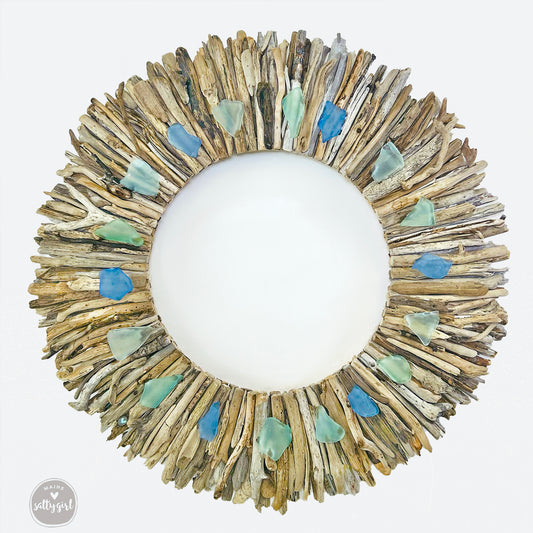 a circular mirror made out of driftwood and sea glass