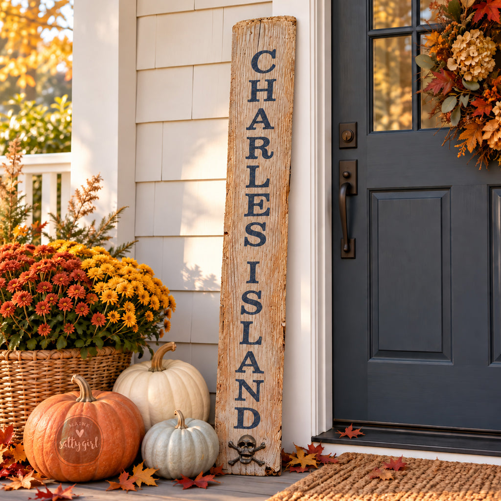 a porch decorated for fall with a wooden sign that reads "CHARLES ISLAND" and several pumpkins and mums.
