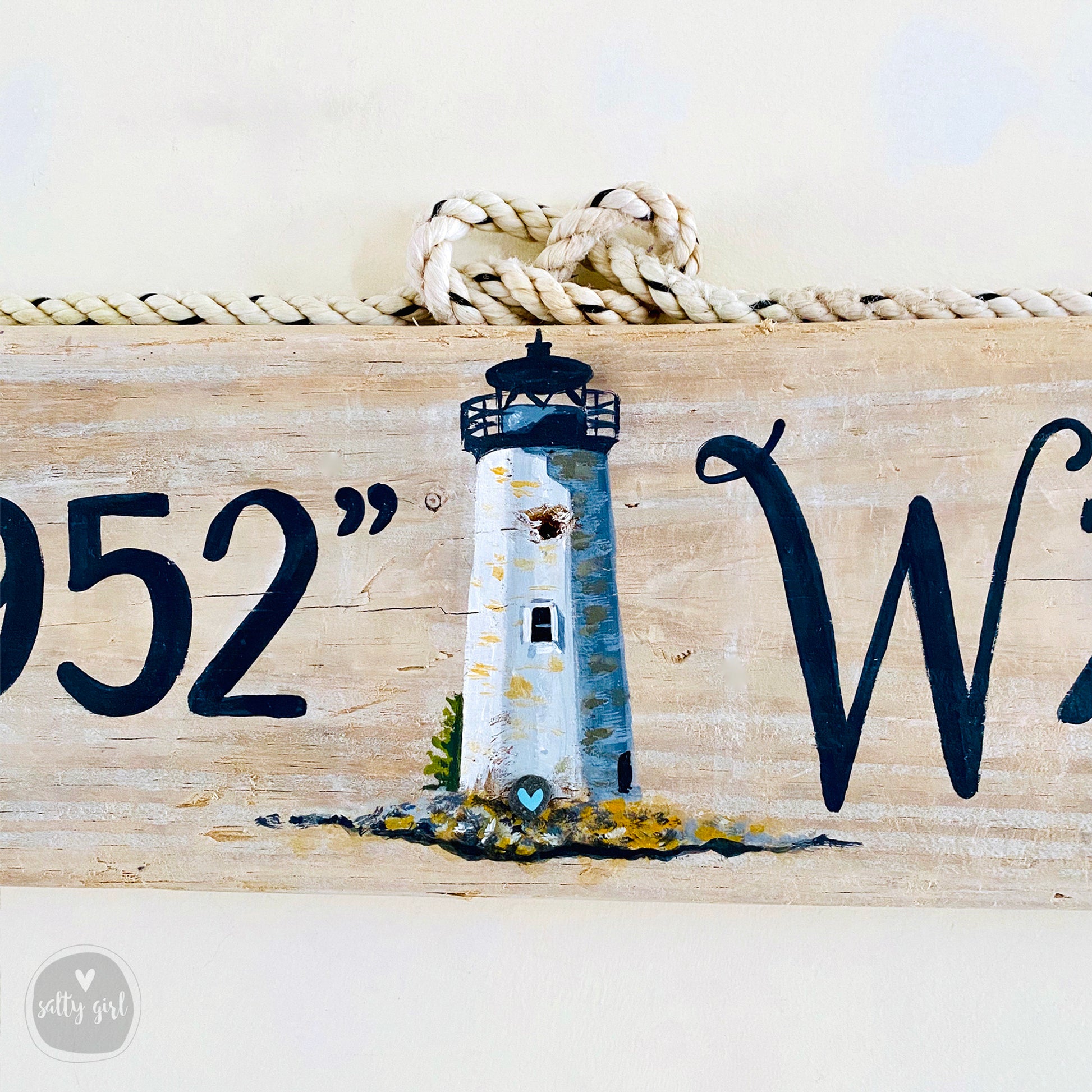 a wooden sign with a lighthouse painted on it