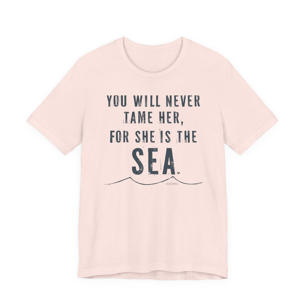 A light pink t-shirt with the text "YOU WILL NEVER TAME HER, FOR SHE IS THE SEA" printed on it.