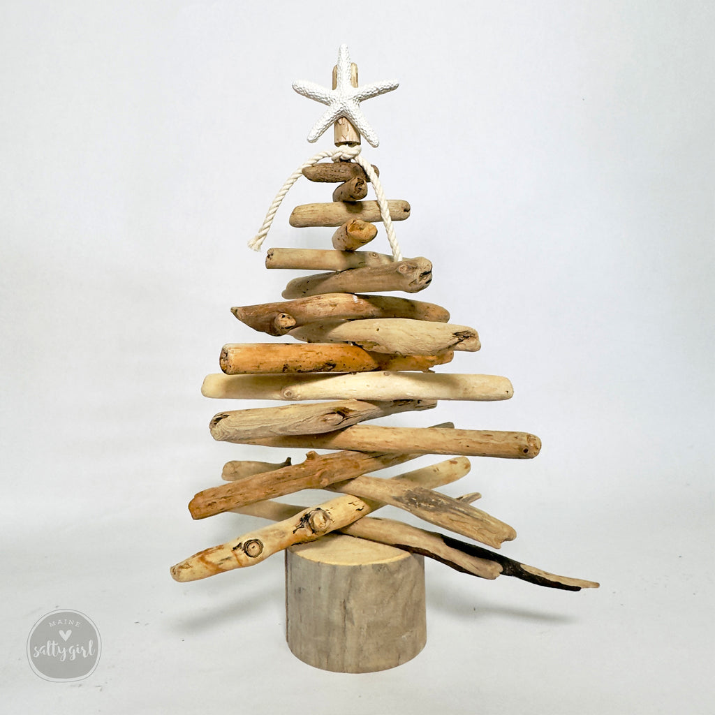 A creative and unique Christmas tree made from various driftwood pieces, including a starfish, arranged in a rustic and natural style.