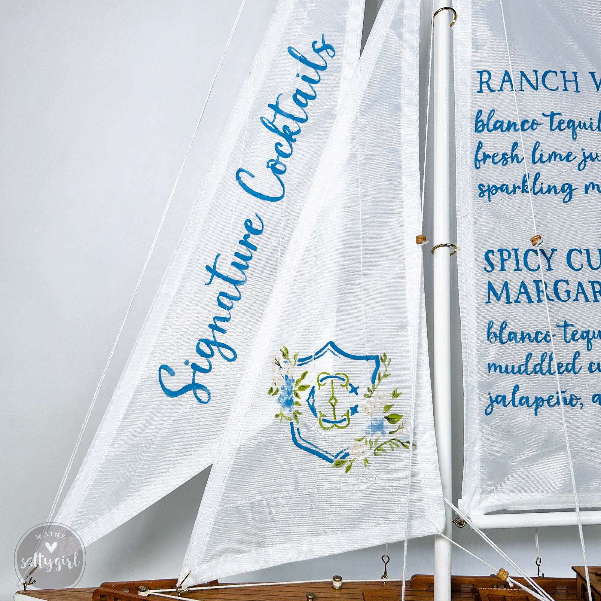 a close-up view of a white sailboat with decorative text and a floral design on it.
