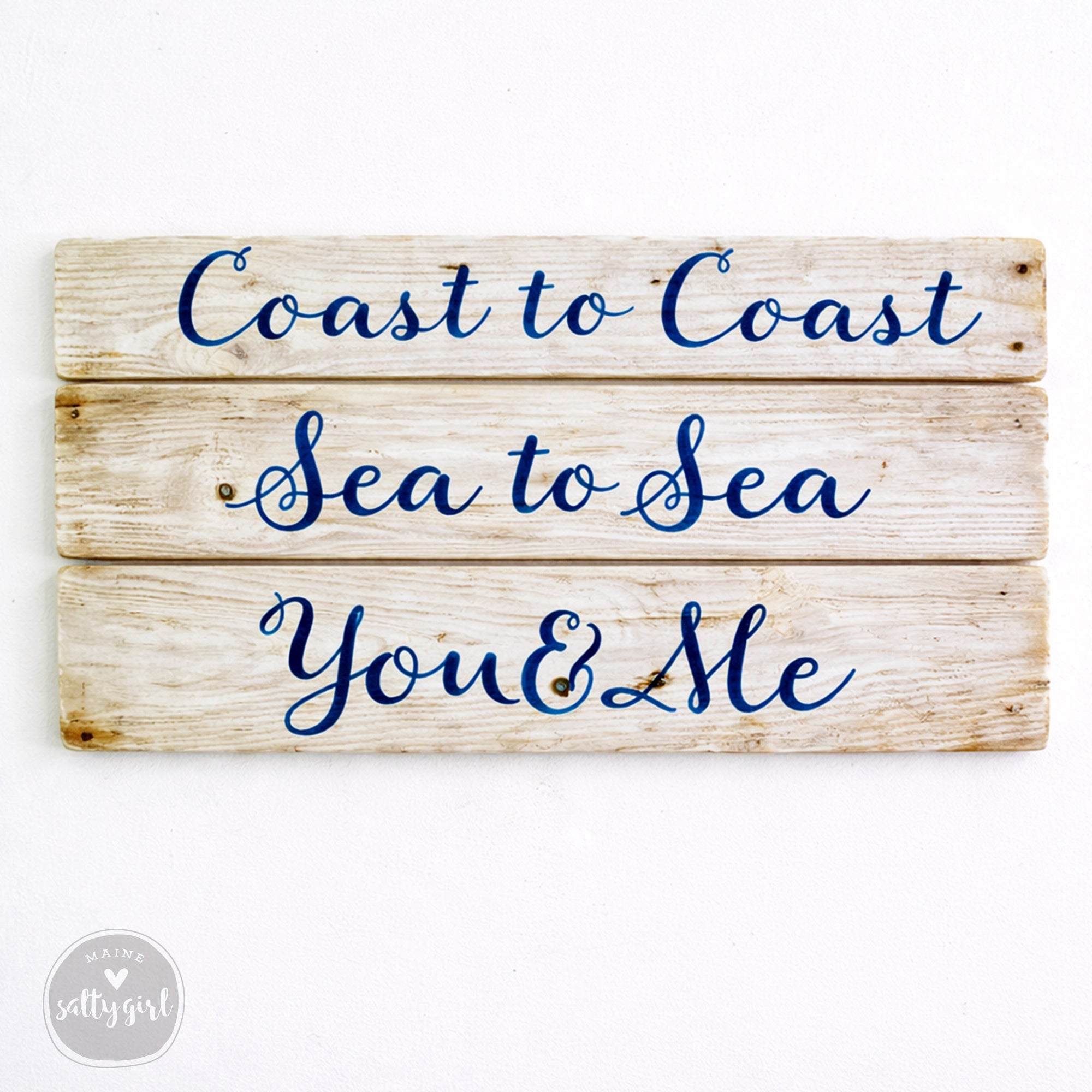 A wooden sign with the text "Coast to Coast Sea to Sea You & Me" written on it.