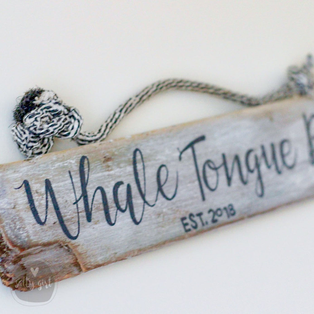 A wooden sign with the name "Whale Tongue" written on it, along with the year "EST. 2013".