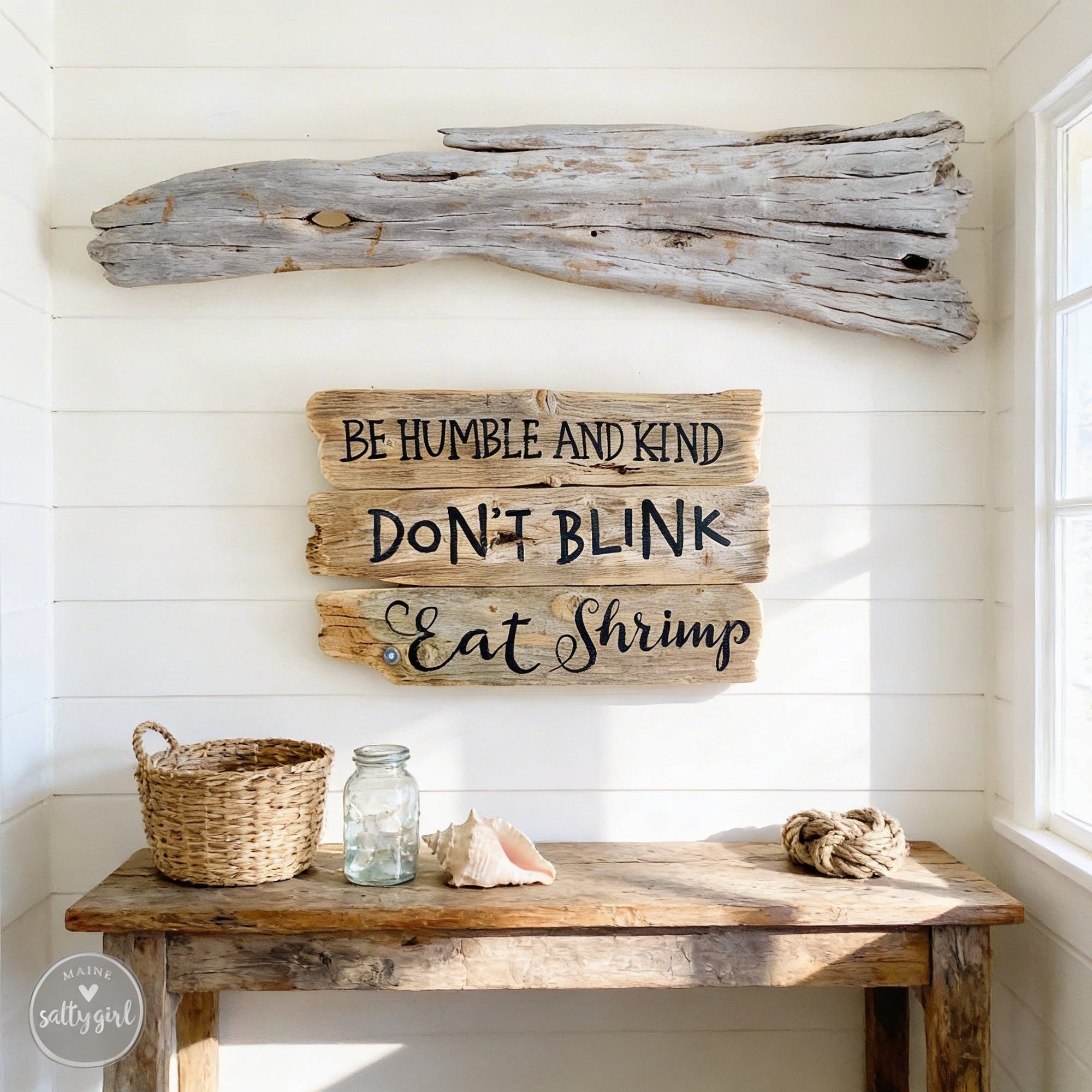 a rustic wooden table with a woven basket, a glass jar, and a seashell, accompanied by a wooden sign with the message "Be Humble and Kind, Don't Blink, Eat Shrimp" above it.