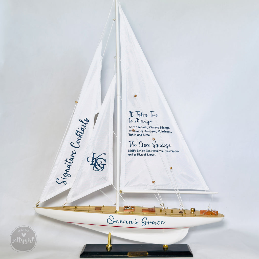 A model of a sailboat with a sign on the mast that reads "Signature Cocktails" and "Ocean's Grace".