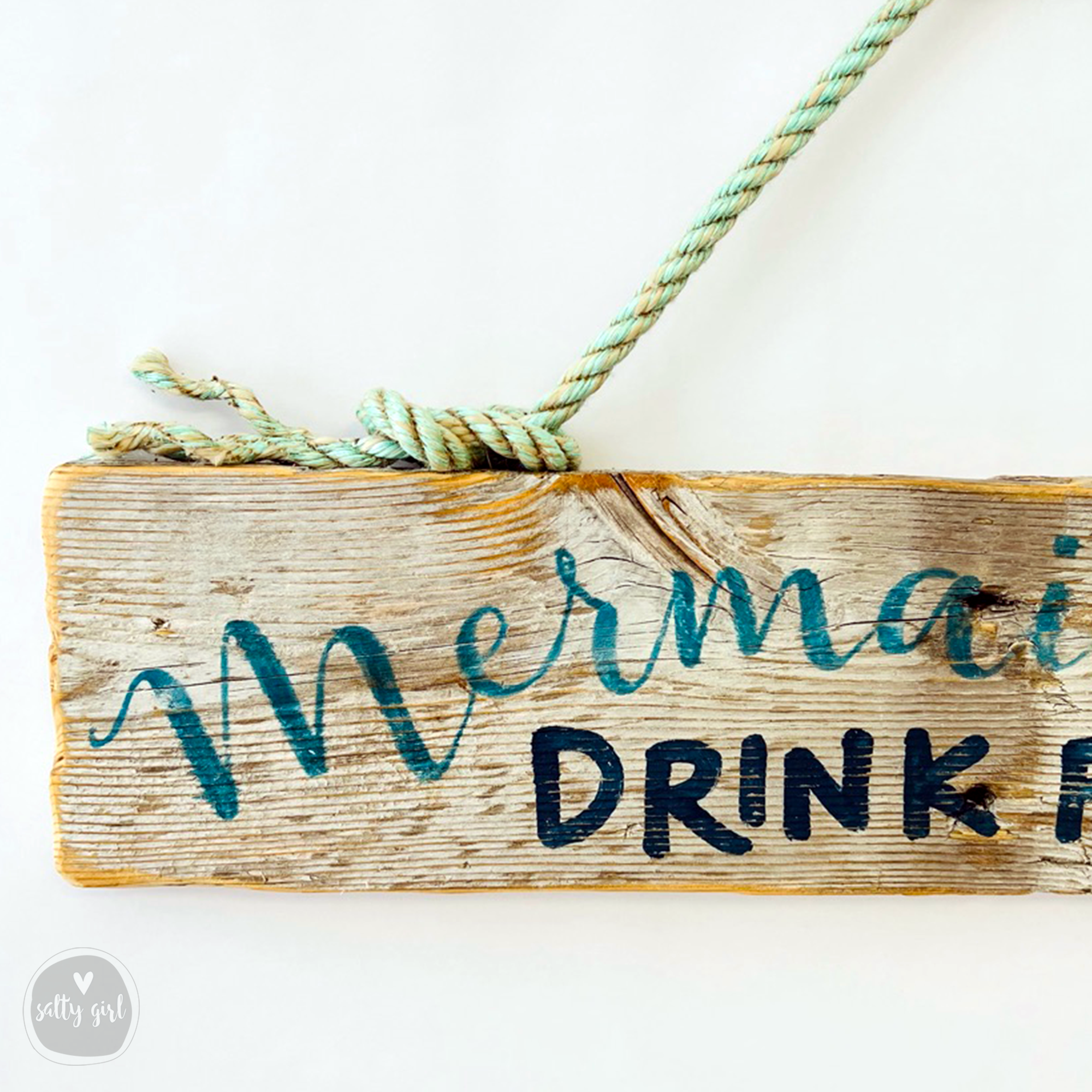 A wooden sign with the text "Mermaid DRINK" written on it, with a green rope tied around it.