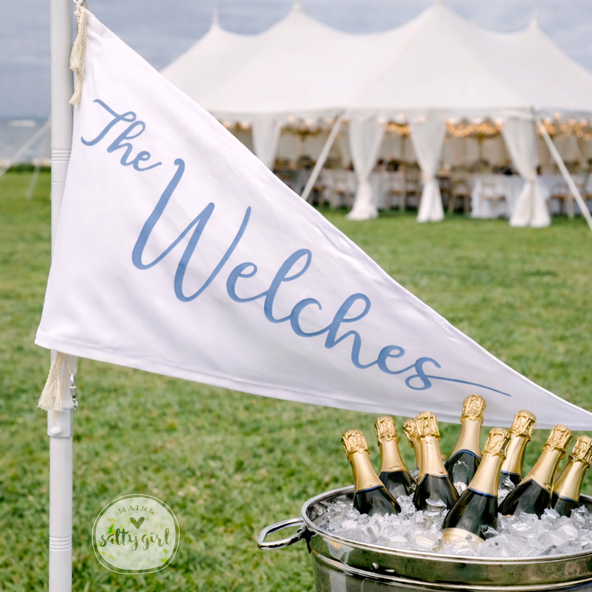 a banner with the name "The Welches" written on it, and a bucket filled with champagne bottles placed in front of it.