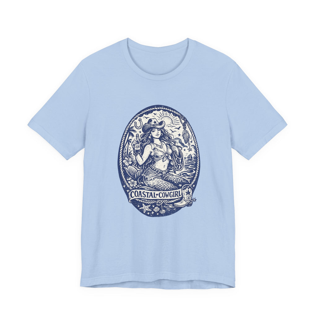 A light blue Maine Salty Girl t-shirt with a graphic design featuring a mermaid or mermaid-like figure surrounded by various elements, including a lighthouse, waves, and a boat.