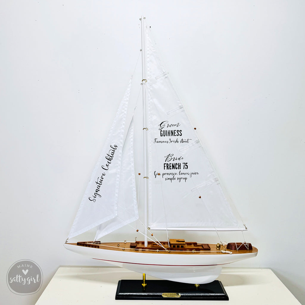 A white model sailboat with the text "Irish Cream" on its sails, displayed on a black base.