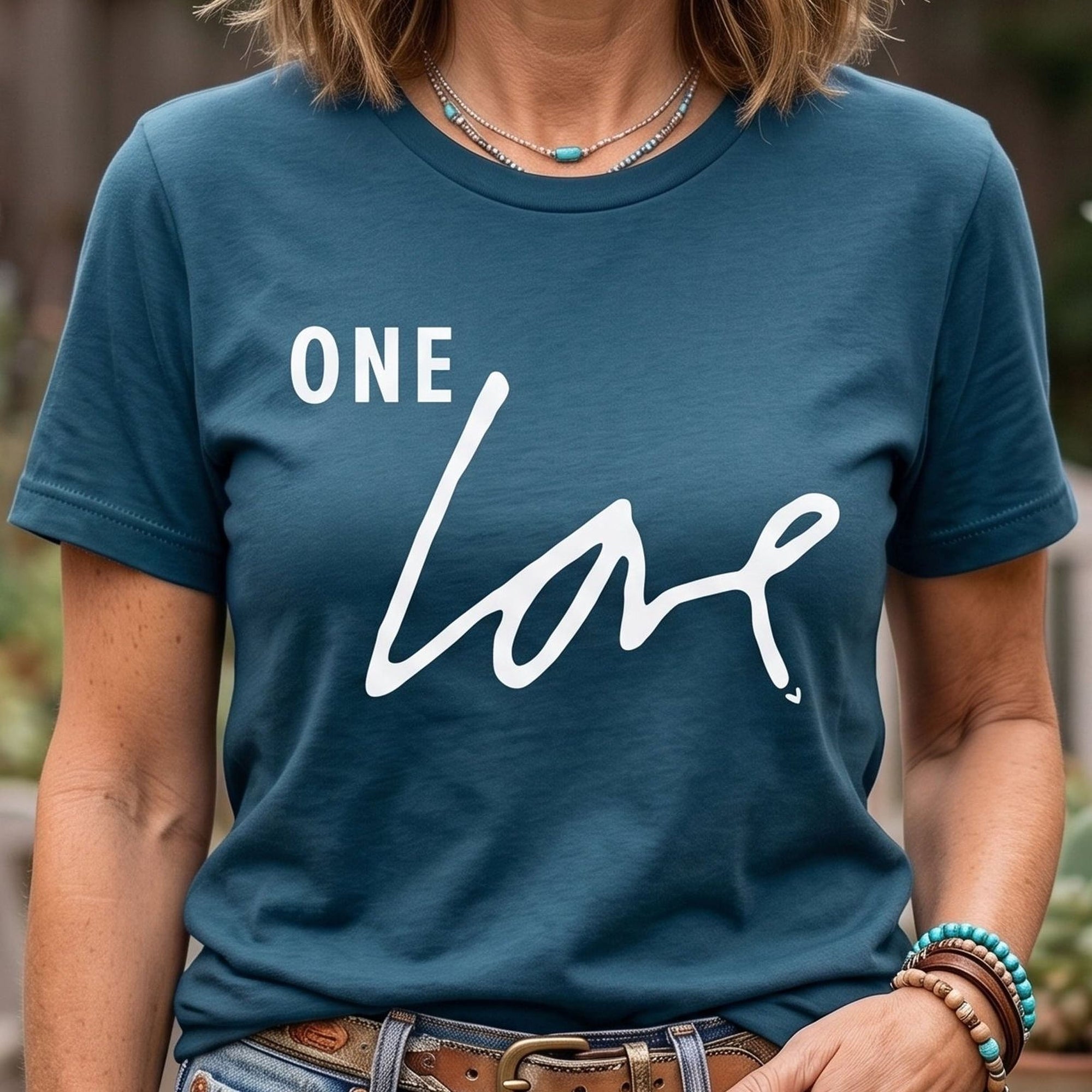 Person wearing a blue Maine Salty Girl t-shirt with 'ONE LOVE' text in an outdoor setting