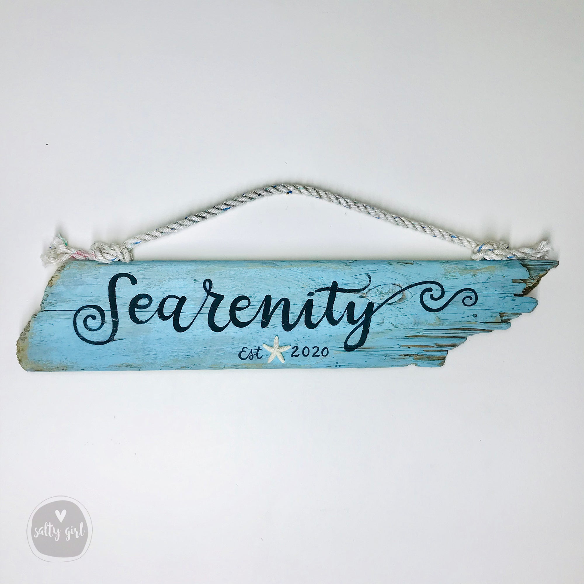 A blue wooden sign with the word "Searenity" written on it, hanging on a rope.