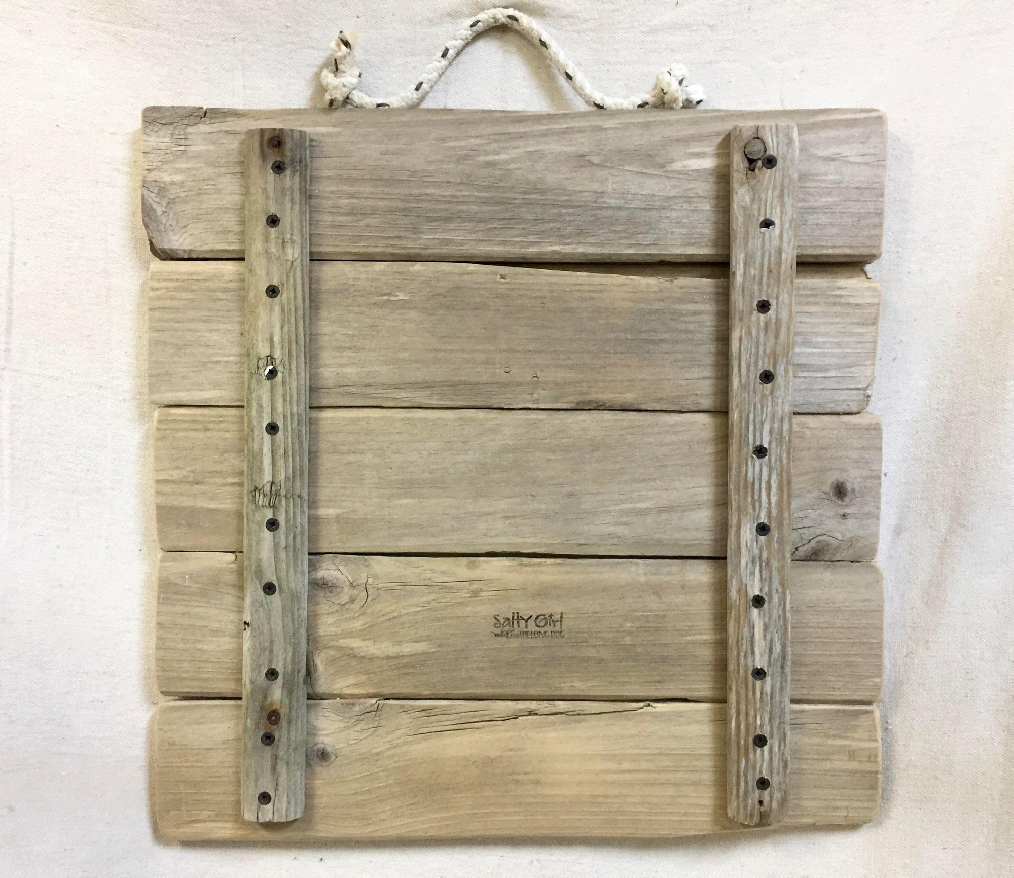 a wooden plank with two metal brackets attached to it, hanging on a wall.