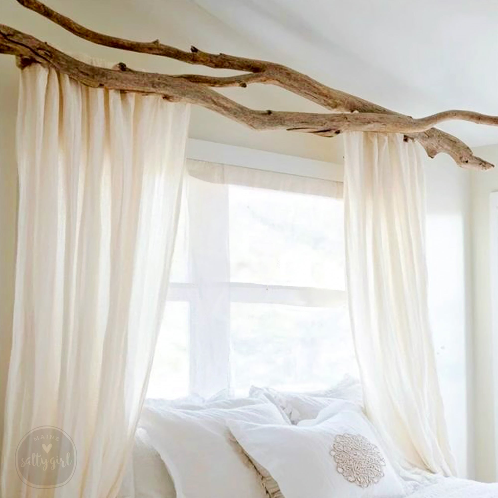 a bedroom with a bed, white curtains, and a large window.