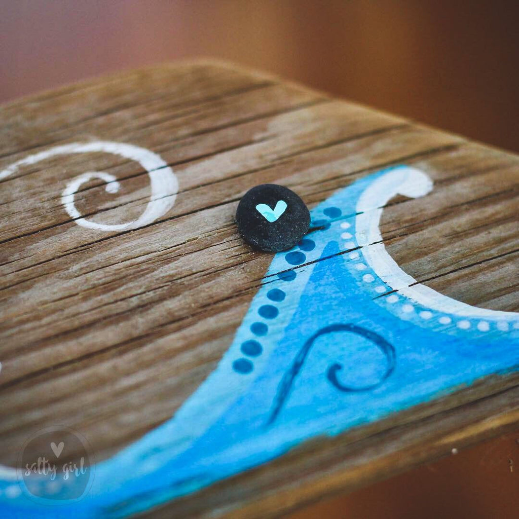 a wooden surface with a blue and white design, including a heart-shaped object and a swirling pattern.