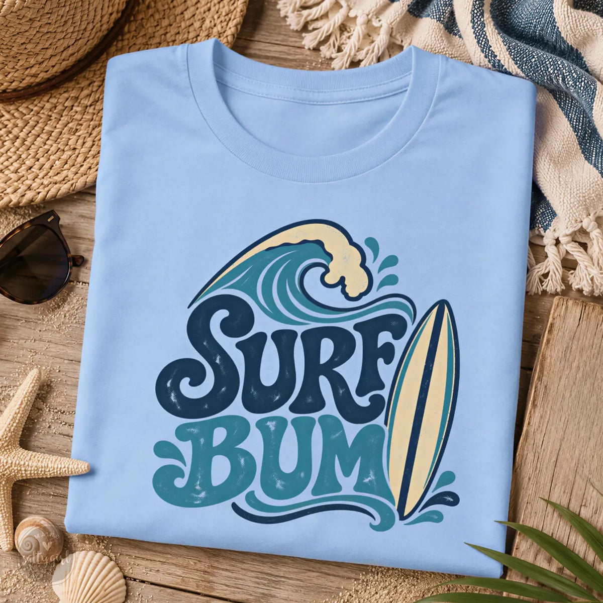A blue t-shirt with a graphic design featuring a surfboard and the text "Surf Bum" printed on it, along with some beach-related items such as a hat, sunglasses, and a starfish.