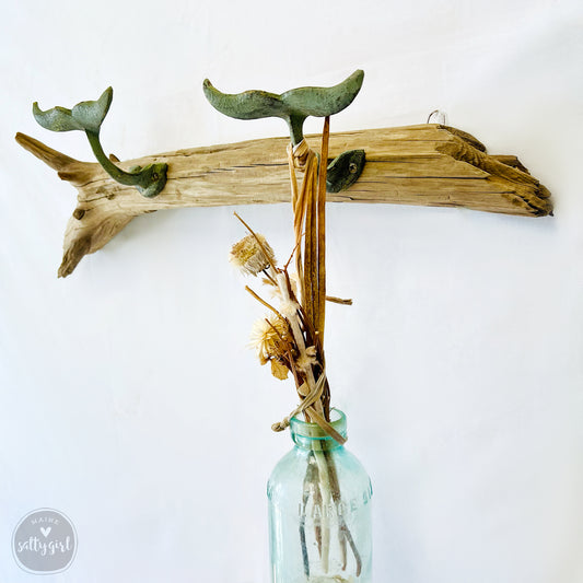 a vase filled with dried flowers on top of a wooden branch