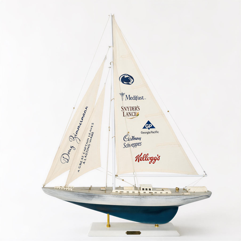 A model sailboat with a sail displaying various company logos, including Mediast, Switchers, LANCE, Cadbury, and Kellogg's.