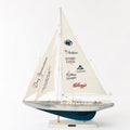 A model sailboat with a sail displaying various company logos, including Mediast, Switchers, LANCE, Cadbury, and Kellogg's.