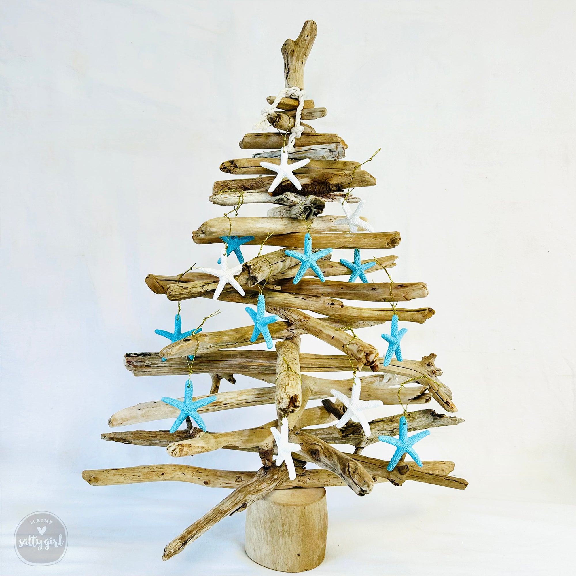 A unique, handcrafted Christmas tree made from driftwood, adorned with blue and white starfish ornaments.