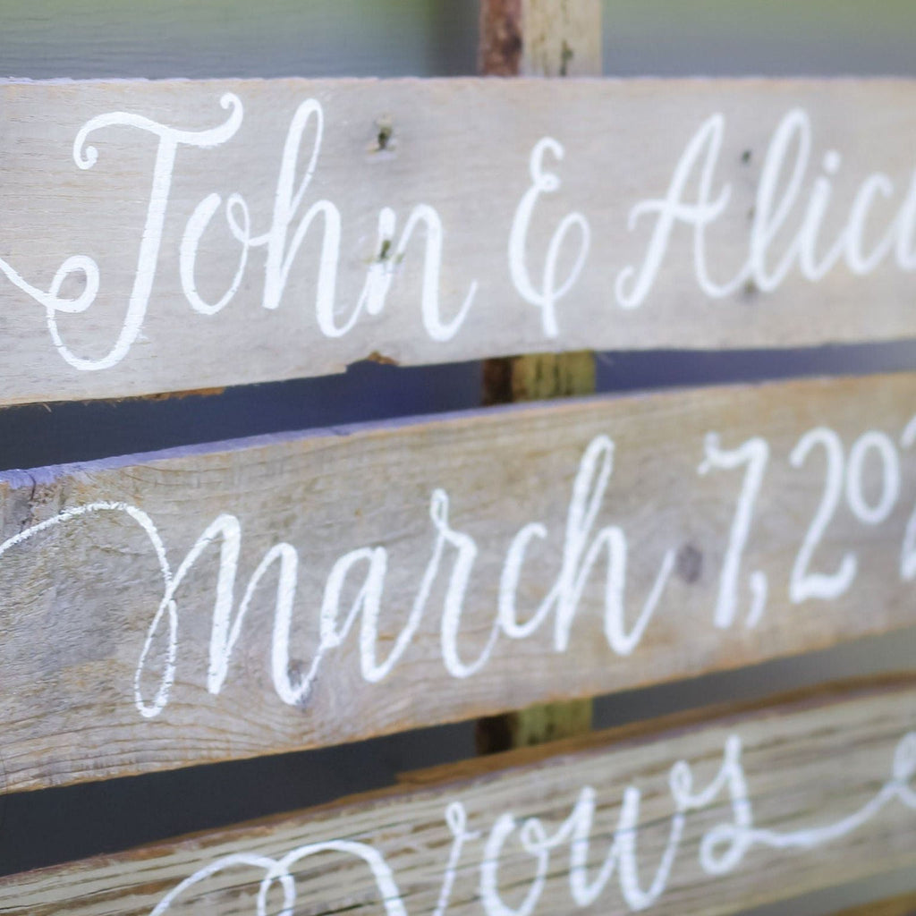 A wooden sign with the names "John & Alice" written on it, along with the date "March 7, 2012".