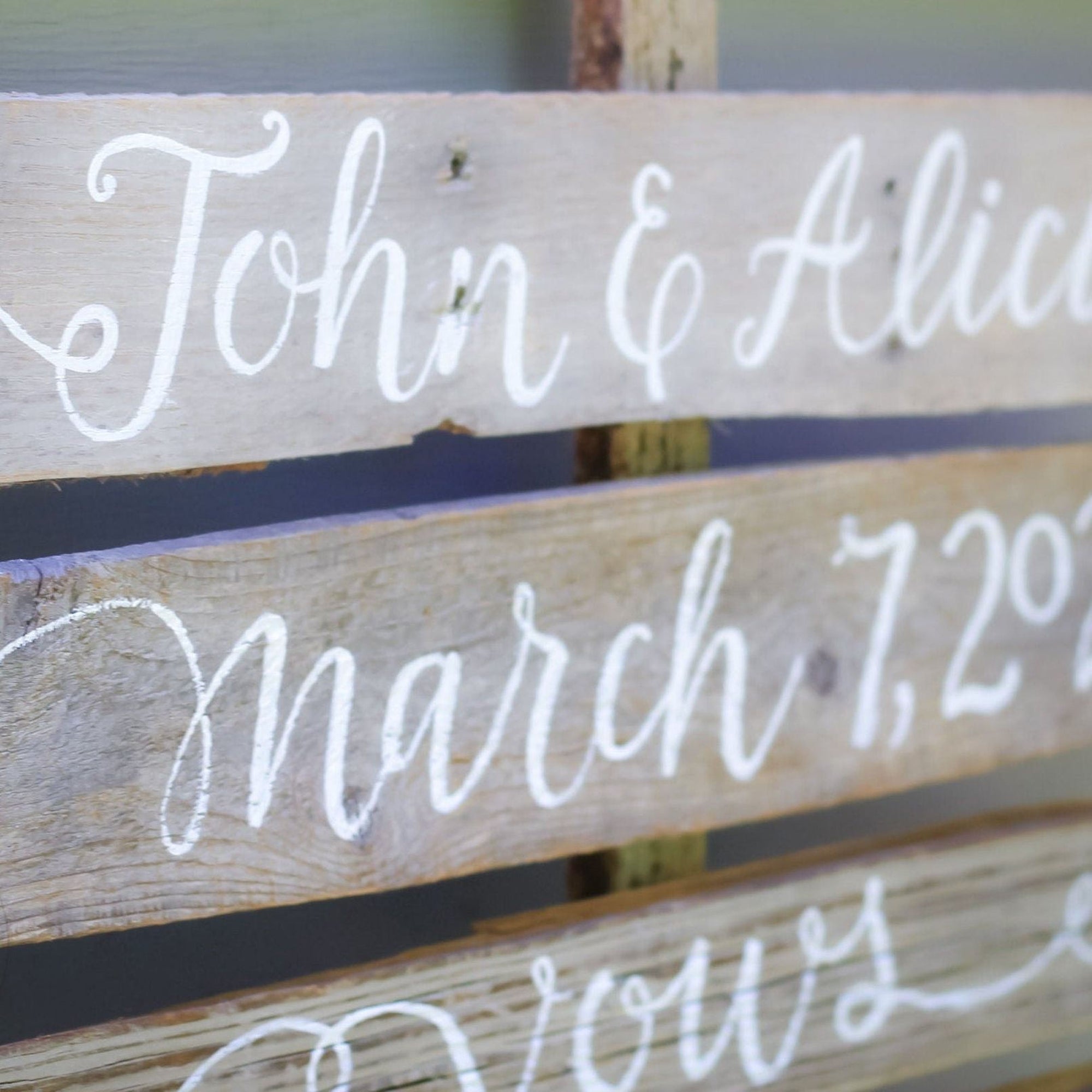 A wooden sign with the names "John & Alice" written on it, along with the date "March 7, 2012".
