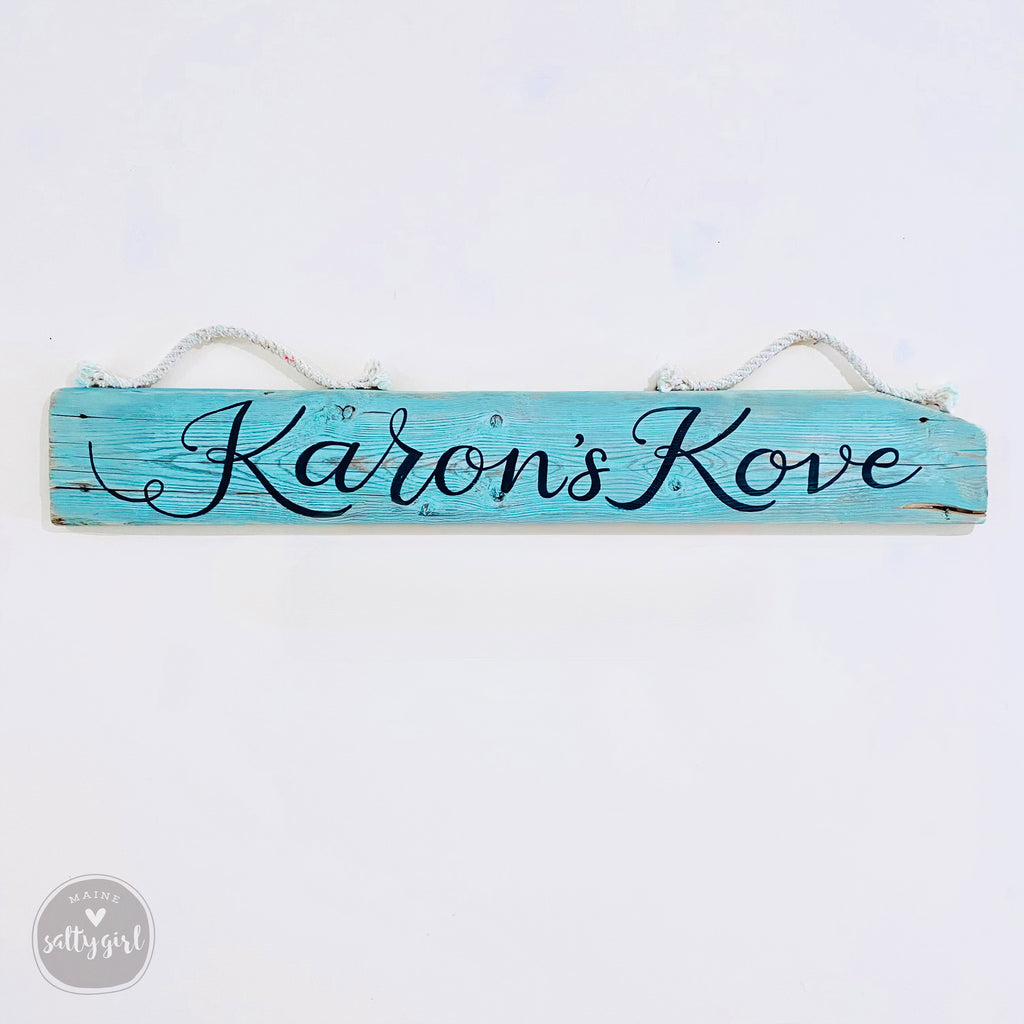 A wooden sign with the name "Karoon's Kove" written on it in cursive lettering.