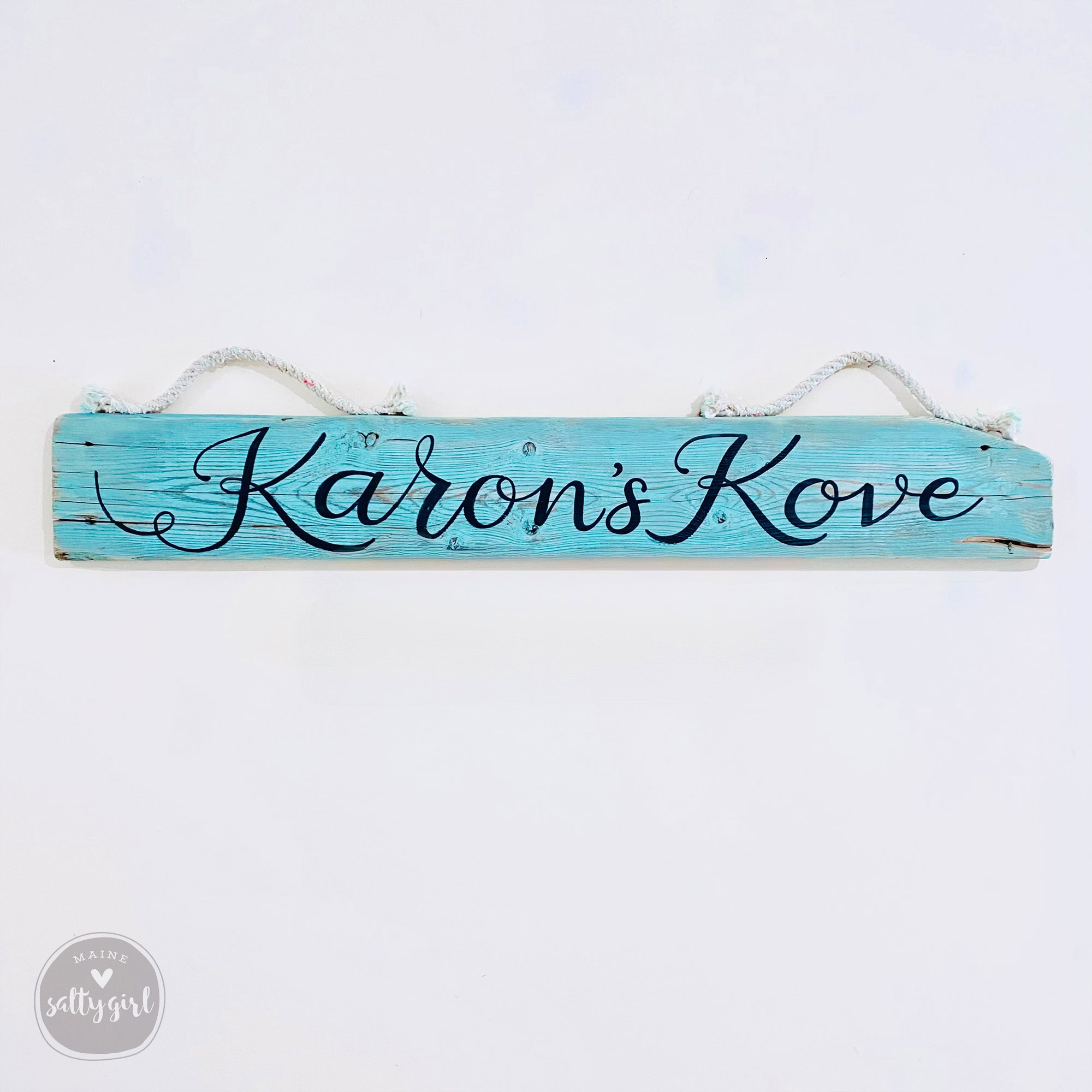 A wooden sign with the name "Karoon's Kove" written on it in cursive lettering.