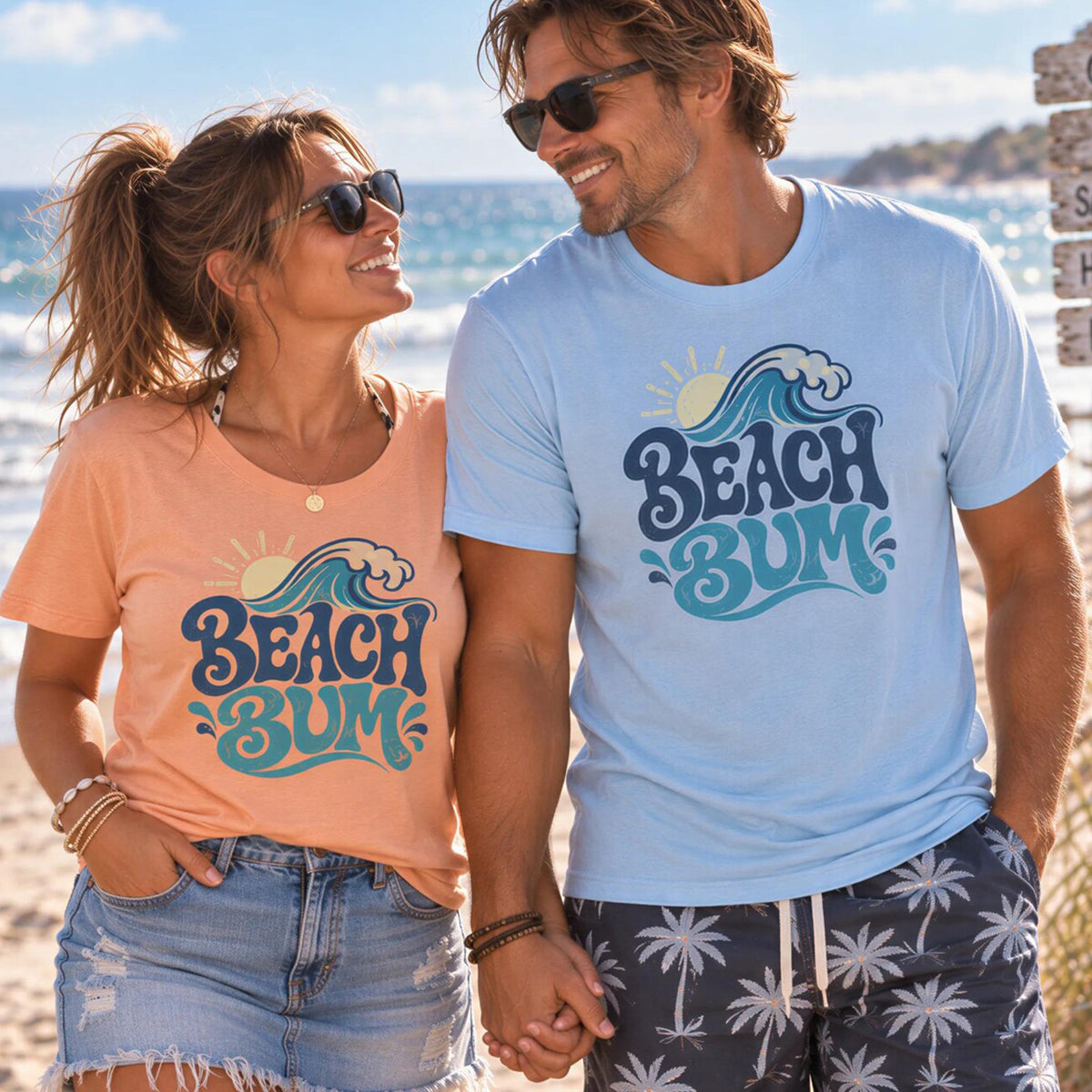 A man and a woman standing together on a beach, both wearing t-shirts with the text "BEACH BUM" printed on them.