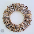 A wreath made of various natural materials, including sticks, branches, and leaves, arranged in a circular pattern.
