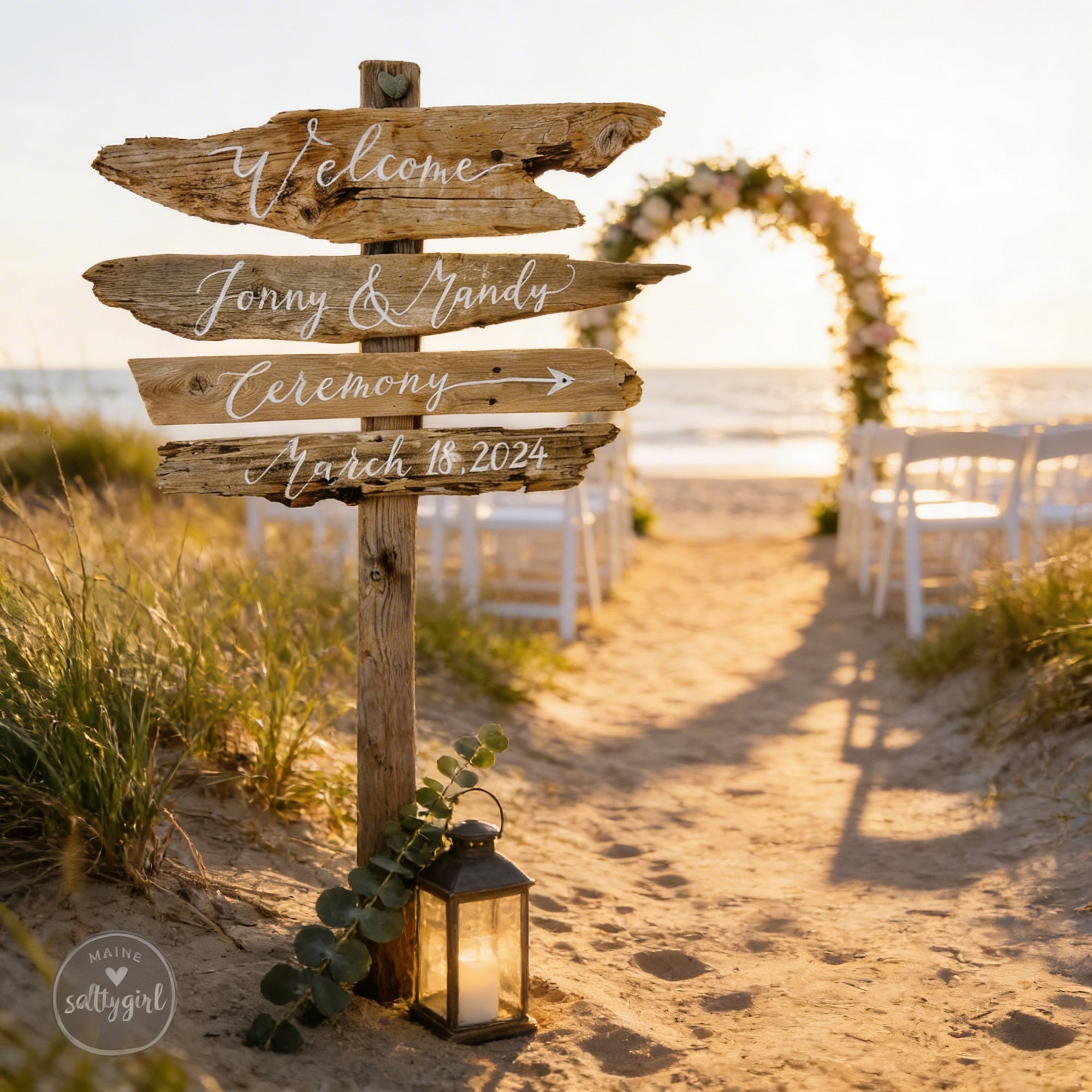 a wooden sign welcoming guests to a wedding ceremony, with a beach setting and a decorated archway in the background.