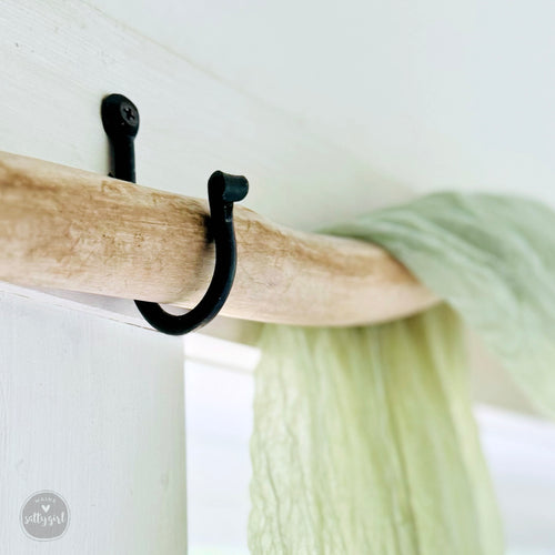 a close up of a black hook on a white wall