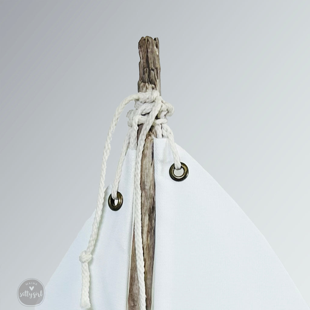 A white sailboat-shaped object with a wooden stick and white rope attached to it.