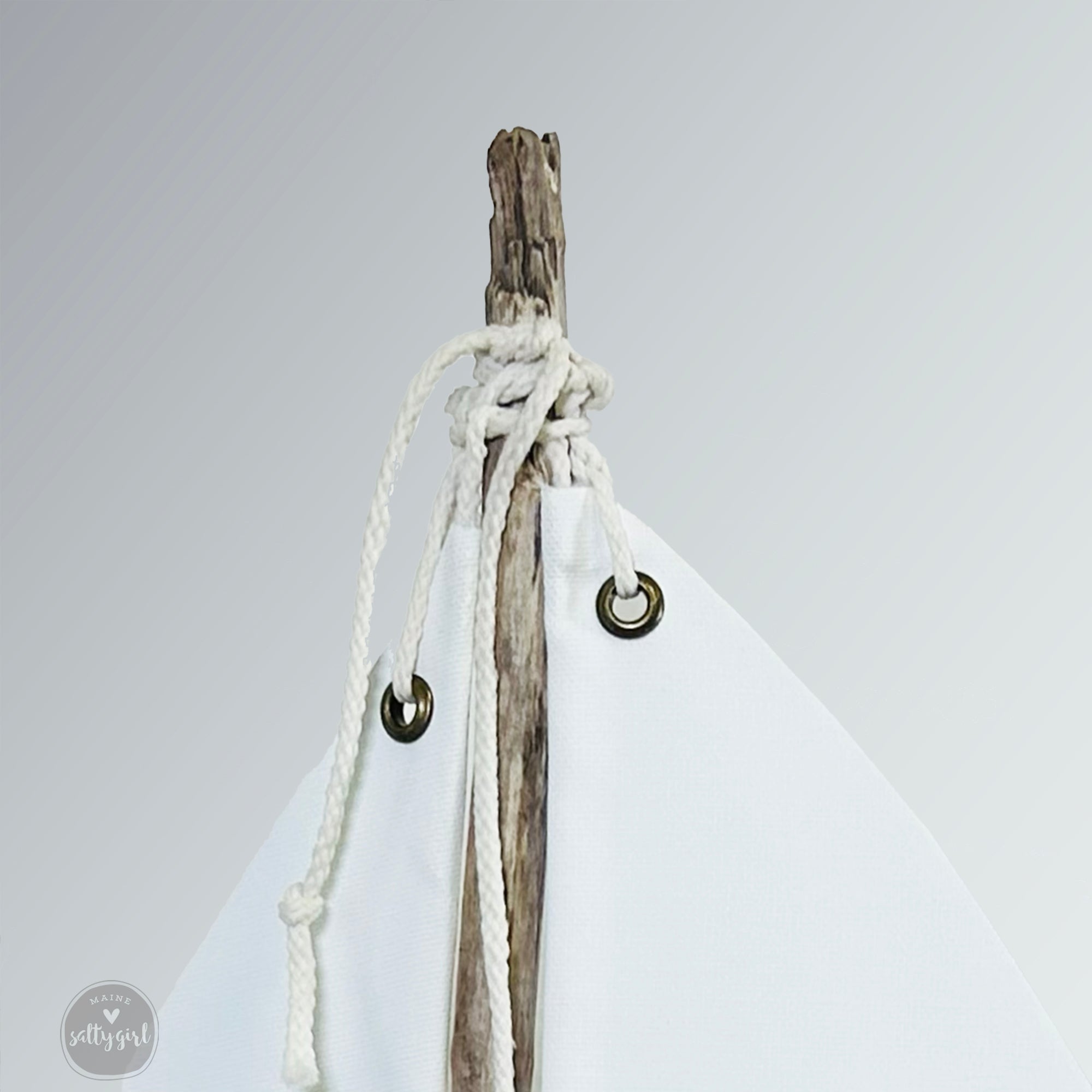 A white sailboat-shaped object with a wooden stick and white rope attached to it.